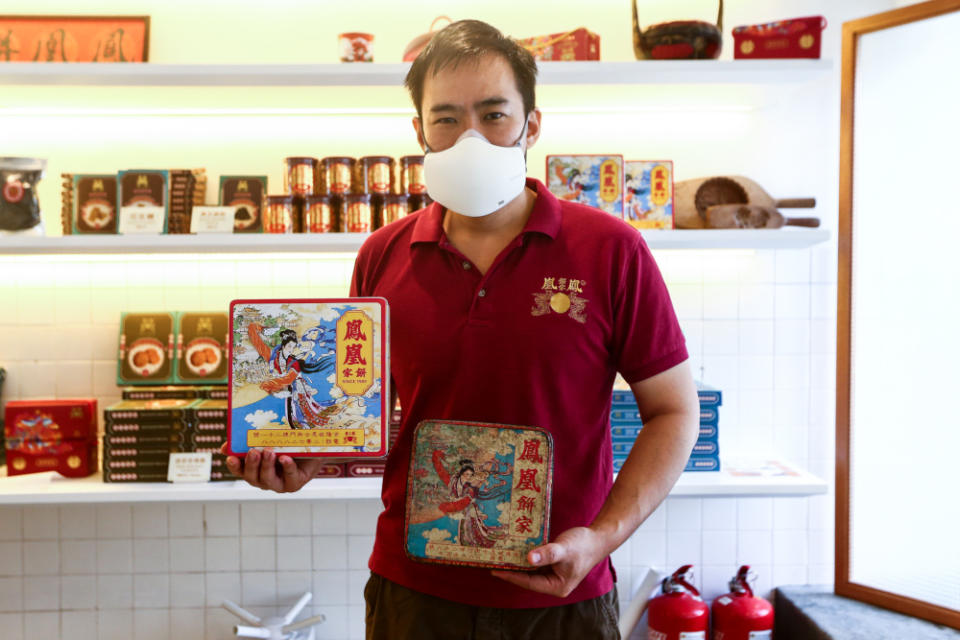 Melvin Chan holds up both the original and recreated version of Fung Wong's tin boxes, with the wooden mould and black and red basket seen in the background. — Picture by Ahmad Zamzahuri