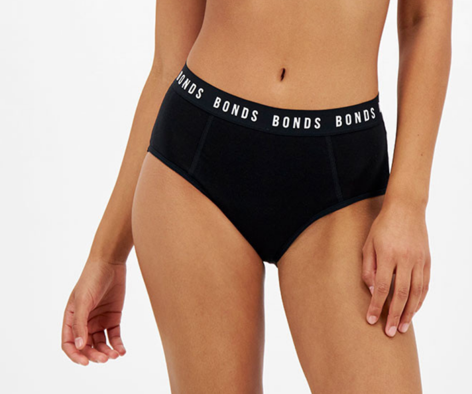 A female model wears black Bonds bloody comdy period undies.