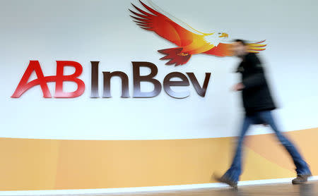 A man walks past the logo of Anheuser-Busch InBev at the brewer's headquarters in Leuven, Belgium February 26, 2014. REUTERS/Francois Lenoir/File photo