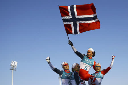 Cross-Country Skiing - Pyeongchang 2018 Winter Olympics - Women's 30km Mass Start Classic - Alpensia Cross-Country Skiing Centre - Pyeongchang, South Korea - February 25, 2018 - Winner Marit Bjoergen of Norway waves the Norwegian flag as she is carried by her teammates. REUTERS/Carlos Barria