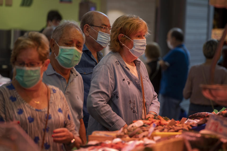 Customers buy fish at a market in Barcelona, Spain, Friday, July 17, 2020. Health authorities are asking Barcelona's 5.5 million residents to reduce their socialization to a minimum and to stay at home as much as possible to stem the spread of the new coronavirus. (AP Photo/Emilio Morenatti)