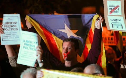 A man with his tapped mouth holds an Estelada (Catalan separtist flag) during a gathering in support of the members of the dismissed Catalan cabinet - Credit: Reuters