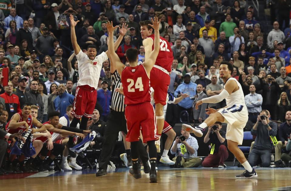 Villanova guard Jalen Brunson (1) follows through on a final shot as Wisconsin players celebrate the end of their second-round men's college basketball game in the NCAA Tournament, Saturday, March 18, 2017, in Buffalo, N.Y. (AP Photo/Bill Wippert)