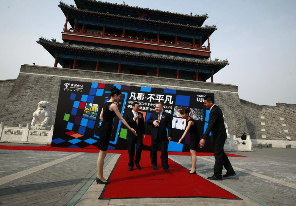 Nokia CEO Stephen Elop, third from right and Wang Xiaochu, Chairman of China Telecoms, second from left, are shown the way for a photo shoot as they arrive to attend the launch of the new Nokia smartphone Lumia 800C in Beijing, China, Wednesday, March 28, 2012. Struggling cellphone maker Nokia launched its first smartphone design for China on Wednesday, looking to the world's biggest mobile market to help drive a turnaround.(AP Photo/Ng Han Guan)