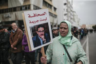 A woman carries a banner of detained journalist Taoufik Bouachrine during a demonstration in Rabat, Morocco, Sunday, April 21, 2019. Protesters are condemning prison terms for the leader of the Hirak Rif protest movement against poverty and dozens of other activists. Banner in Arabic read "Journalism is not a crime." (AP Photo/Mosa'ab Elshamy)