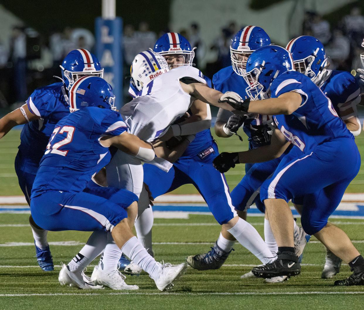 Lake’s Charlie Christopher (32) and teammates tackle DeSales’s quarterback Pj Noles during their Division II regional quarterfinal at Lake Blue Streak Stadium, Friday, Nov. 4, 2022.