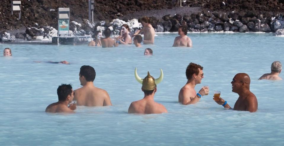 Visitors enjoy drinks while swimming in the geothermal pool