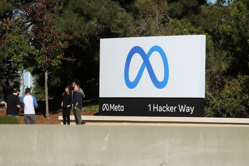 People pose for a photo in front of Facebook's new rebrand logo Meta at its headquarters in Menlo Park