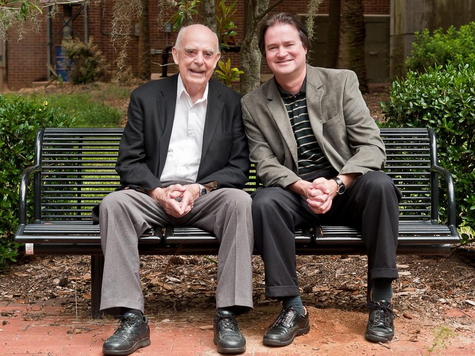 Former FSU Professor Raymond Sheline (left) sits on the Raymond K. Sheline Bench on the university's campus donated by the Sheline children in 1992, with FSU Professor Mark Riley (right) in 2011.