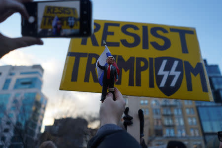 A protester holds up a Trump figurine to take a photo with a protest sign during a demonstration against U.S. President Donald Trump on Presidents' Day in Union Square, New York, U.S., February 18, 2019. REUTERS/Go Nakamura