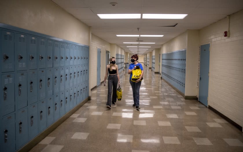 WOODLAND HILLS, CA - APRIL 30: Sophomore Kerry Miller, left, walks out with her mom Holly Miller, right, after bagging up books and cleaning out her locker at El Camino Real Charter High School on Thursday, April 30, 2020 in Woodland Hills, CA. School officials were allowing no more than 5 students at a time on campus to take home their belongings. ((Brian van der Brug / Los Angeles Times)