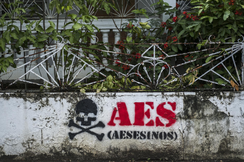 Graffiti reads "AES assassins" at an abandoned house in Guayama. (Photo: Dennis Rivera Pichardo for HuffPost)