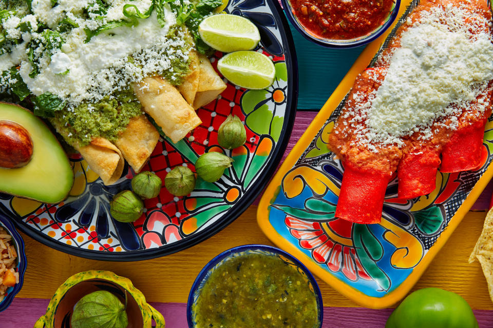 Green and red enchiladas with mexican sauces mix in colorful table