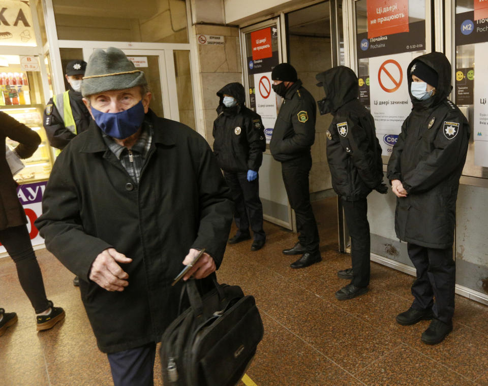 Policeman does not allow a man to enter a subway station because he has no passenger pass in Kyiv Ukraine, Monday, April 5, 2021. The city authorities have tightened an anti-coronavirus lockdown on Monday with more cases registered and hospitals overcrowded. (AP Photo/Efrem Lukatsky)