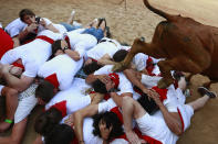 <p>A revellers takes a photo with his cell phone while others protect themselves as a calf jumps over them in the bullring after the 4th day of the running of the bulls at the San Fermin Festival in Pamplona, northern Spain, July 10, 2018. (Photo: Alvaro Barrientos/AP) </p>