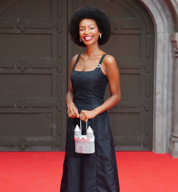 Closeup of Bethany Antonia standing on the red carpet holding a castle-shaped purse