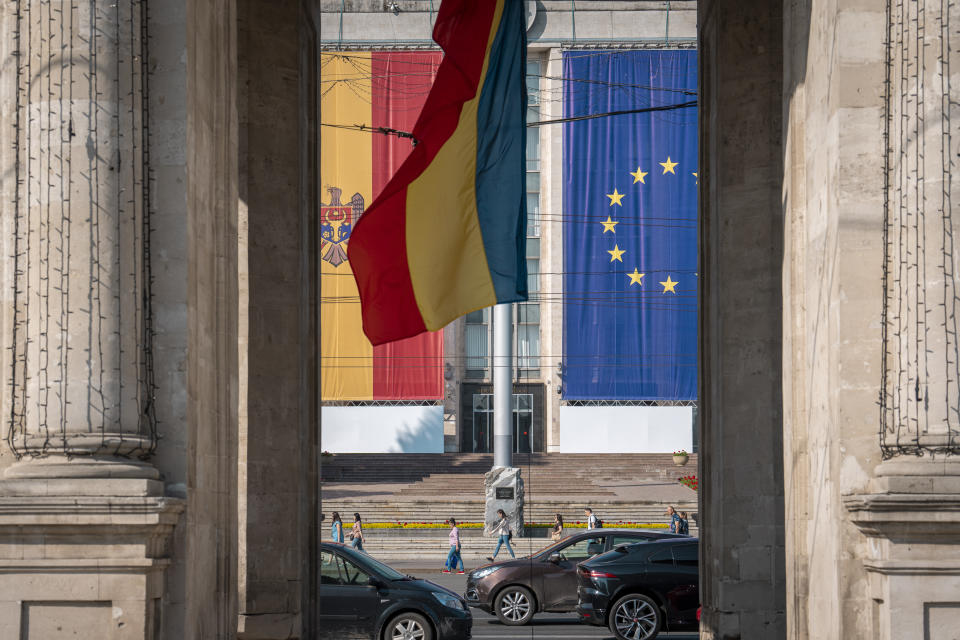 People walk by the government building, decorated with European Union and Moldovan flags in Chisinau, Moldova, Wednesday, May 31, 2023. Moldova will host the Meeting of the European Political Community on June 1, 2023. Preparations for a major summit of European leaders were still underway in Moldova on Wednesday, a sign of the Eastern European country’s ambitions to draw closer to the West and break with its Russian-dominated past amid the war in neighboring Ukraine. (AP Photo/Vadim Ghirda)