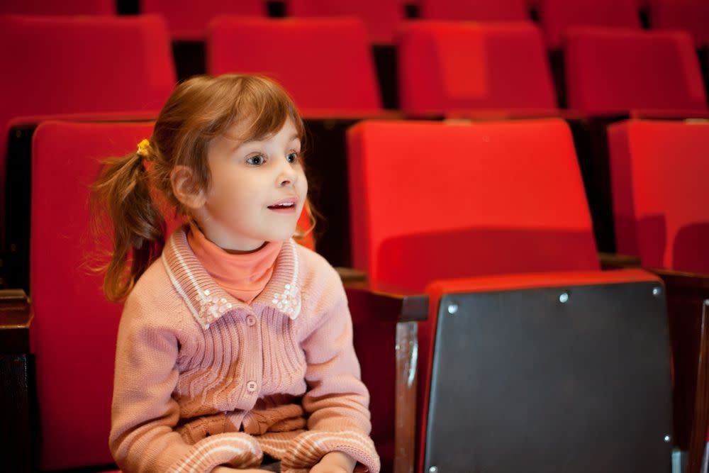 A red haired girl watches a movie.