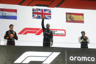 Mercedes driver Lewis Hamilton of Britain waves from the podium after winning the Qatar Formula One Grand Prix. In Lusail, Qatar, Sunday, Nov. 21, 2021. On the left is second placed Red Bull driver Max Verstappen of the Netherlands and on the right third placed Alpine driver Fernando Alonso of Spain. (Hamad I Mohammed, Pool via AP)