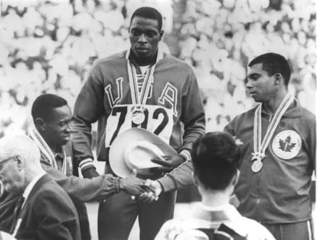 Oct 15, 1964:  Olympic gold medal winner Robert Hayes watches as silver medal winner Enrique Figuerola congratulates bronze medallist Harry Jerome, right.  