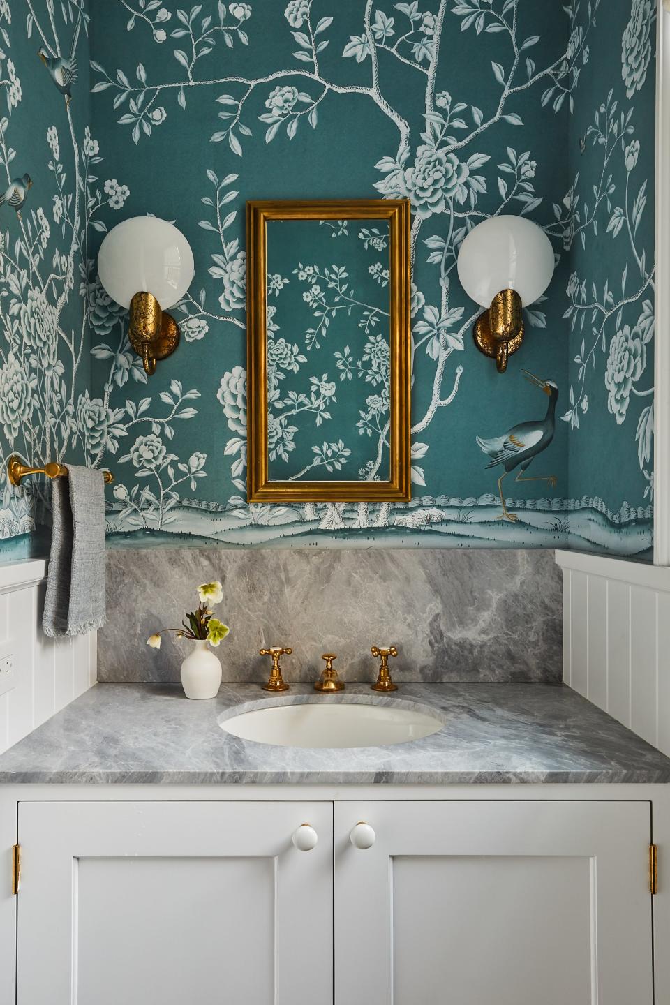 “I always feel like the powder room should be a little more fun,” says Kamel. Here, custom De Gournay wallpaper becomes a lively backdrop for Urban Electric Company sconces and an Ann-Morris mirror.