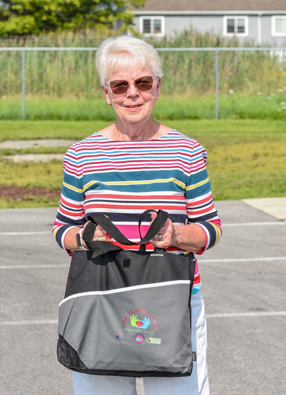 6558 Grand Success Coordinator Mary Ann Widmer provides a great deal of support to her tutors. Each one receives a bag like the one she is holding here that contains customized resources that will help the tutor’s student thrive.