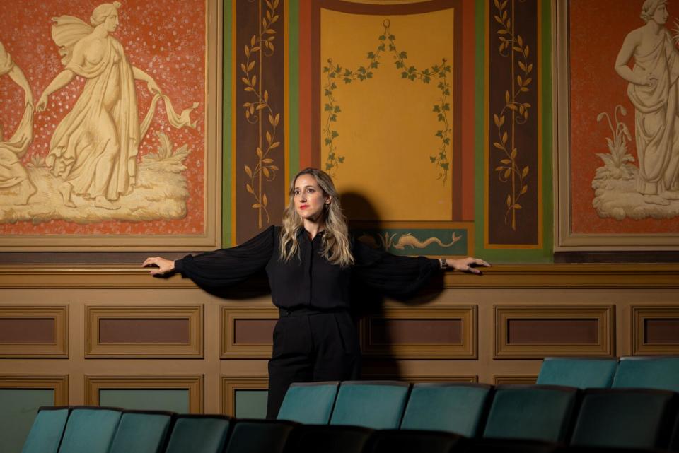 A woman leaning against the wall of a theater.