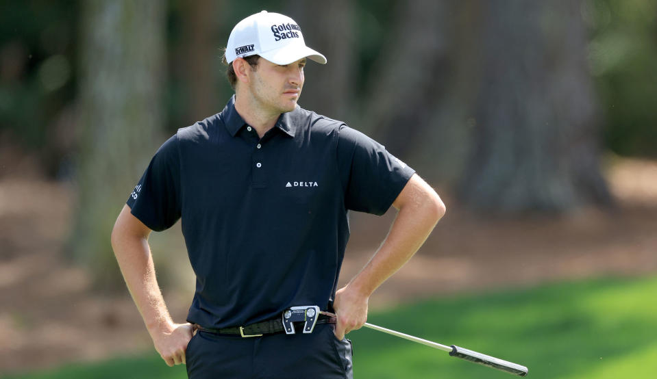 Cantlay puts his hand on his hips as he holds his putter 