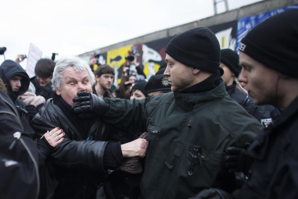 German police struggles with a protestor as they protect a part of the former Berlin Wall in Berlin, Germany, Friday, March 1, 2013. Berliners are protesting as a construction company removes a section of a historic stretch of the Berlin Wall known as the East Side Gallery to provide access to a riverside plot where luxury condominiums are being built. Since German reunification, the stretch of the wall has been preserved as a historical monument and transformed into an open air gallery painted with colorful murals, and has become a popular tourist attraction. (AP Photo/Markus Schreiber)