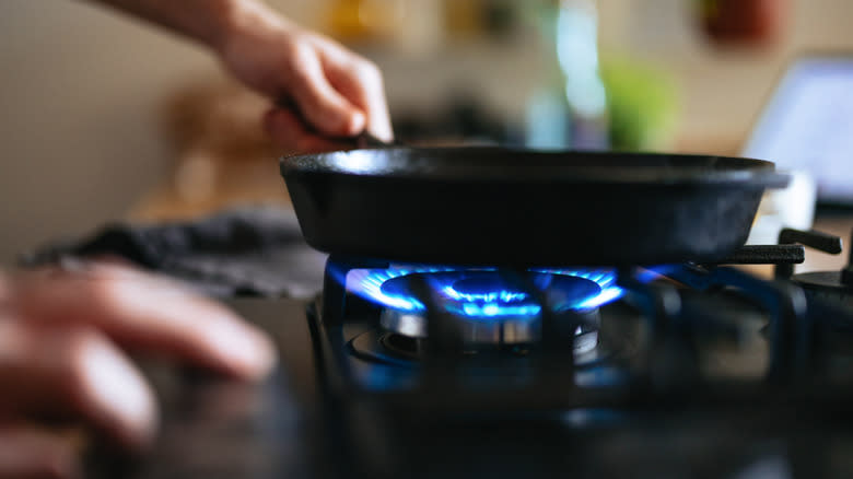 Woman putting skillet on gas