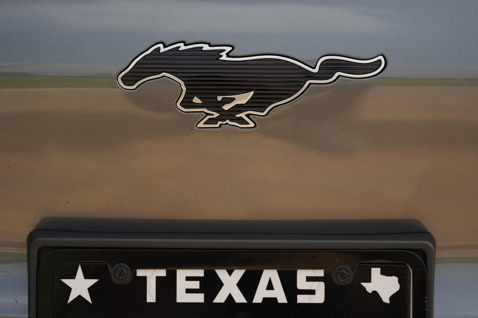 A Ford Mustang Mach-E logo is seen of a vehicle Thursday, May 9, 2024, in San Antonio. Many Americans still aren’t sold on going electric for their next car purchase. High prices and a lack of easy-to-find charging stations are major sticking points, a new poll shows. (AP Photo/Eric Gay)