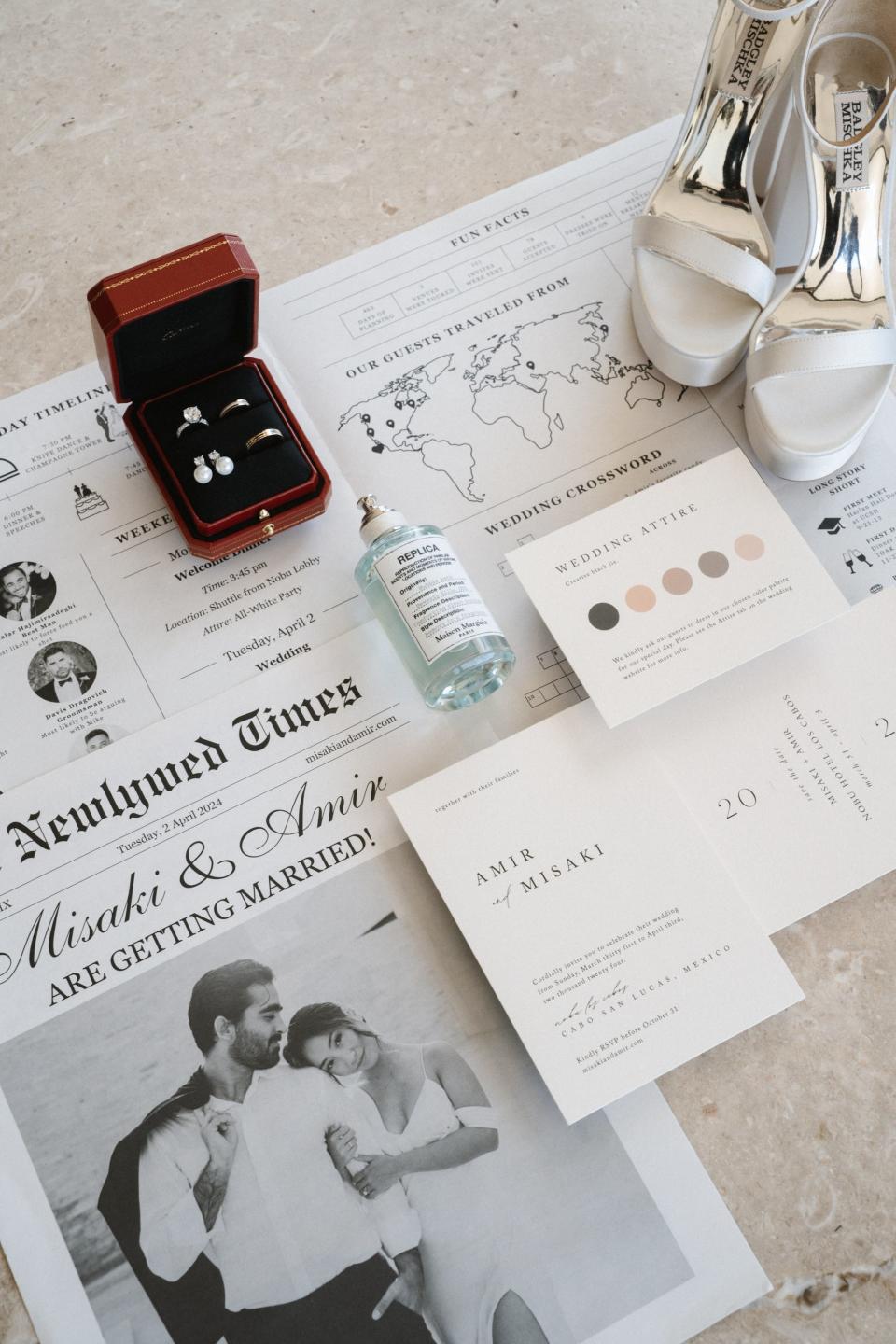 A suite of wedding invitations, shoes, and a wedding ring box sit atop a newspaper spread.