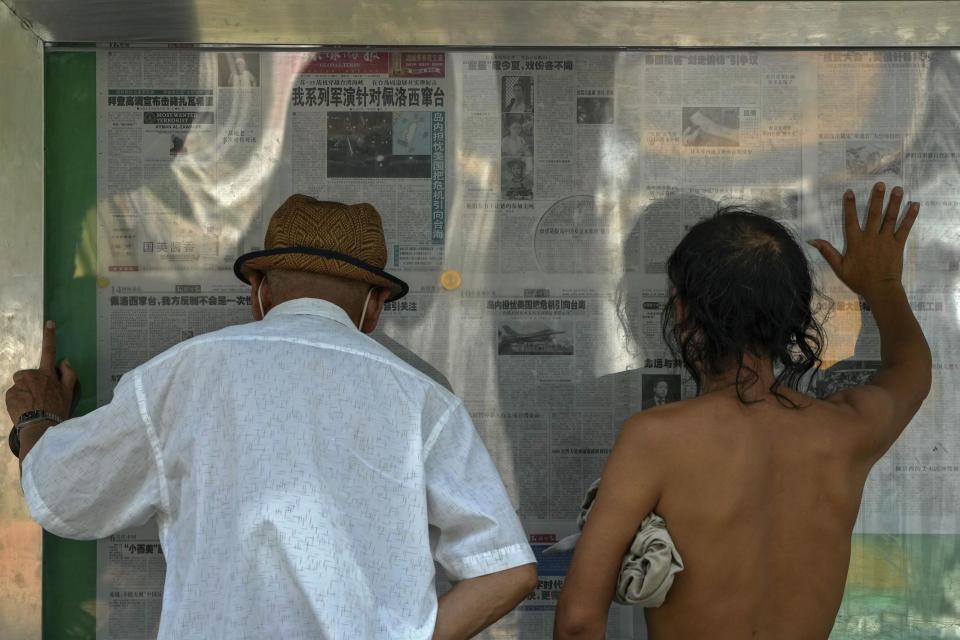 Residents read a newspaper with a photo of a plane carrying U.S. House Speaker Nancy Pelosi lands at Songshan Airport in Taipei, Taiwan with a headline reporting "Our series of military exercises are aimed at Pelosi channeling Taiwan" at a stand in Beijing, Wednesday, Aug. 3, 2022. After weeks of threatening rhetoric, China stopped short of any direct military confrontation with the U.S. over the visit of Pelosi to Taiwan. The response disappointed some Chinese, who asked why no action was taken to stop her. (AP Photo/Andy Wong)