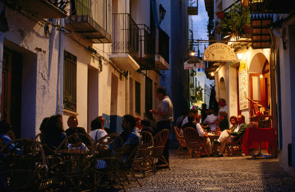 People dining at outdoor restaurant in an alleyway with ambient lighting