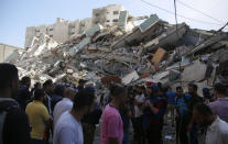 People gather at in front of a building housing AP office and other media in Gaza City that was destroyed after Israeli warplanes demolished it, Saturday, May 15, 2021. The airstrike Saturday came roughly an hour after the Israeli military ordered people to evacuate the building. There was no immediate explanation for why the building was targeted. (AP Photo/Hatem Moussa)