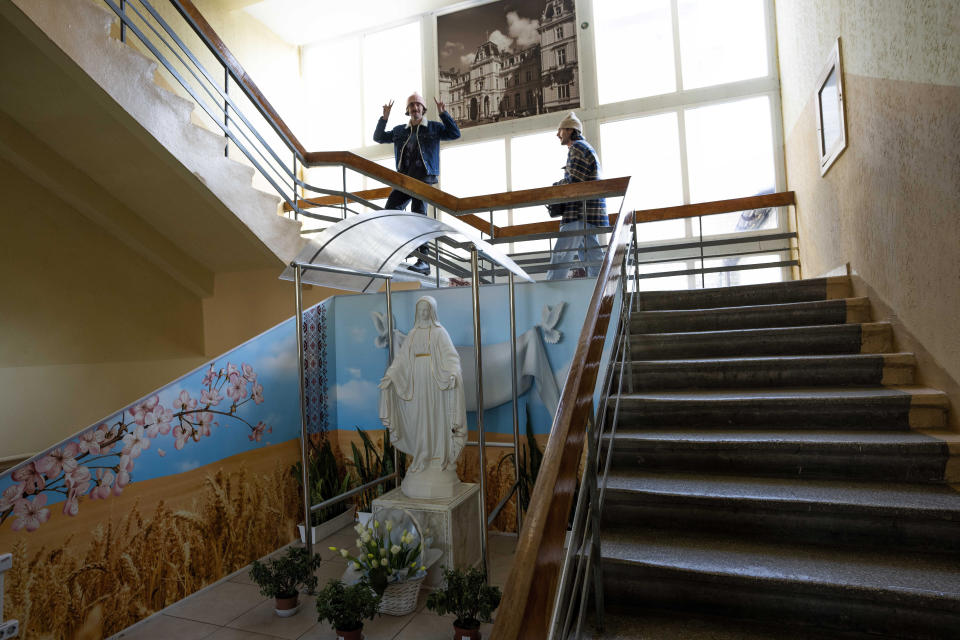 Ukrainian co-founder designer and creative director Ruslan Baginskiy of high-end hat designer brand flashes the victory sign as he makes his way with his partner, public relations director Petro Yasinskiy, inside a college turned into a working space for the company in Lviv, western Ukraine, Friday, March 25, 2022, after fleeing Kyiv. (AP Photo/Nariman El-Mofty)