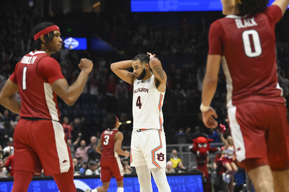 Auburn forward Johni Broome (4) stands on the court as Arkansas guard Ricky Council IV (1) and Anthony Black celebrate after an NCAA college basketball game in the second round of the Southeastern Conference tournament, Thursday, March 9, 2023, in Nashville, Tenn. Arkansas won 76-73. (AP Photo/John Amis)