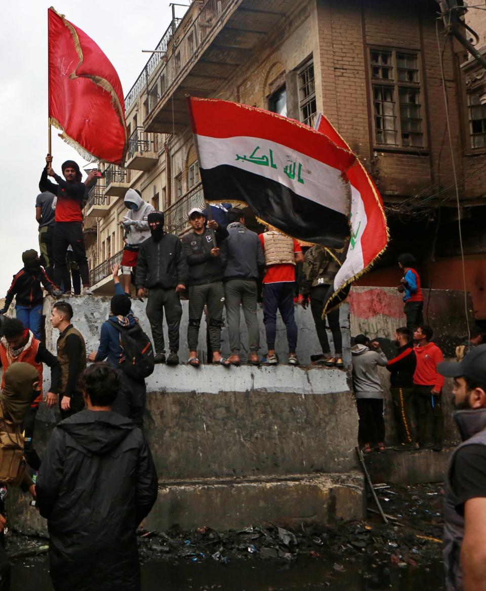 Anti-government protesters gather on barriers set up by security forces to close Rasheed Street during ongoing protests in Baghdad, Iraq, Tuesday, Dec. 3, 2019. At least 400 people have died since the leaderless uprising shook Iraq on Oct. 1, with thousands of Iraqis taking to the streets in Baghdad and the predominantly Shiite southern Iraq decrying corruption, poor services, lack of jobs and calling for an end to the political system that was imposed after the 2003 U.S. invasion. (AP Photo/Khalid Mohammed)