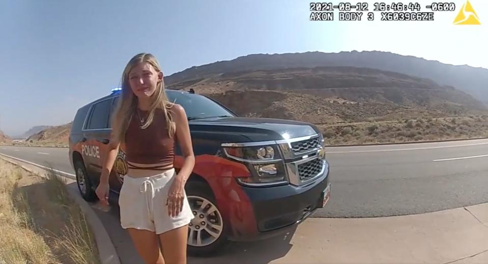 A still of police bodycam footage showing Gabby Petito outside a police car on August 12. She looks upset.