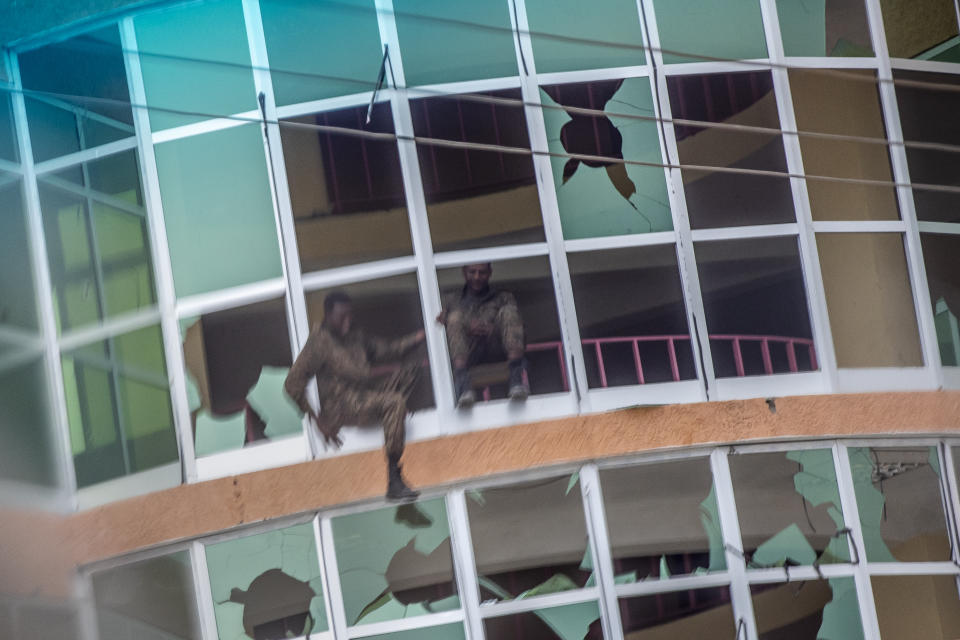 An Ethiopian government soldier climbs out of the broken windows of a building in Abi Adi, in the Tigray region of northern Ethiopia, on Tuesday, May 11, 2021. In November 2020, asserting that Tigrayan fighters had attacked a military base, Prime Minister Abiy Ahmed sent federal troops into Tigray. Government forces are now allied with militias from the Amhara ethnic group as well as soldiers from neighboring Eritrea, who are blamed for many atrocities. (AP Photo/Ben Curtis)