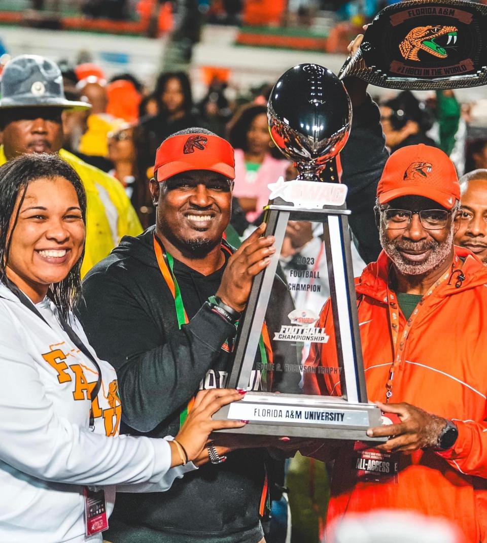 Florida A&M Rattlers head coach Willie Simmons (middle) hoists the Southwestern Athletic Conference Football Championship trophy alongside Florida A&M Vice President and Director of Athletics Tiffani-Dawn Sykes (left) and University President Dr. Larry Robinson (right) after defeating the Prairie View A&M Panthers 35-14 on Ken Riley Field at Bragg Memorial Stadium in Tallahassee, Florida, Saturday, Dec. 2, 2023.