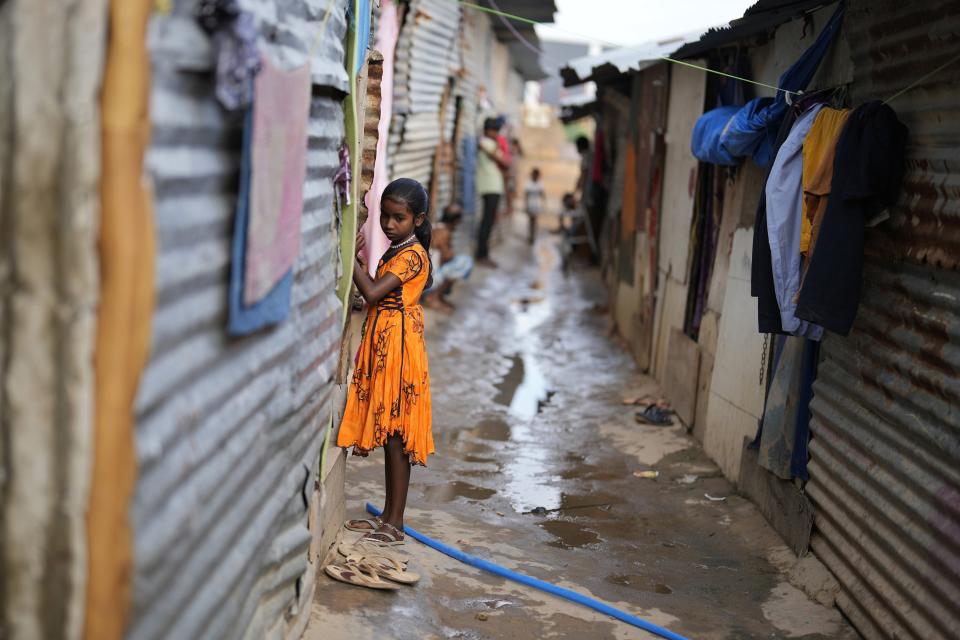 Jerifa Islam stands outside her home in a poor neighborhood in Bengaluru, India, on July 20, 2022. A flood in 2019 in the Darrang district of India's Assam state started Islam, her brother and their parents on a journey that led the family from their Himalayan village to Bengaluru. (AP Photo/Aijaz Rahi)
