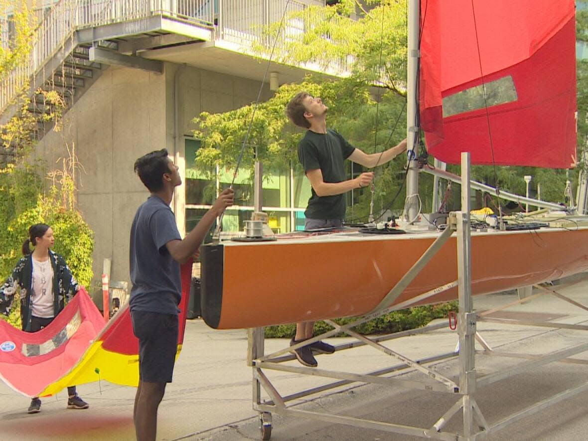 Members of the UBC Sailbot team prepare for this month's launch of their latest robotic, autonomous sailboat. (CBC - image credit)