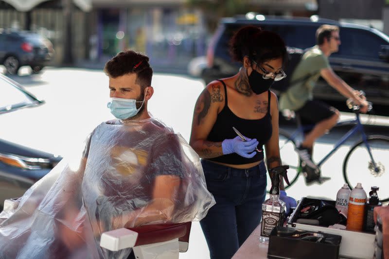 Lulu Castillo, 26, cuts the hair of Joe Nasr, 35, on the street outside Active Barbers, amid the global outbreak of the coronavirus disease (COVID-19), in Santa Monica