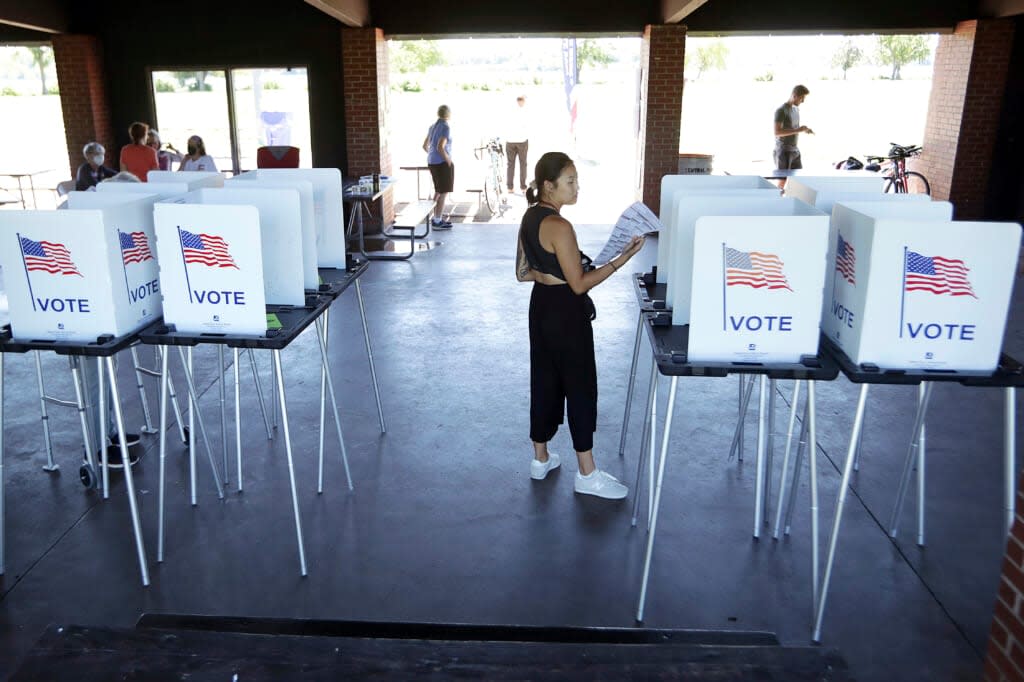 Yuna Seong, center, looks over her completed ballot while voting at the Vilas Park Shelter in Madison, Wis., Tuesday, Aug. 9, 2022. (Kayla Wolf/Wisconsin State Journal via AP)
