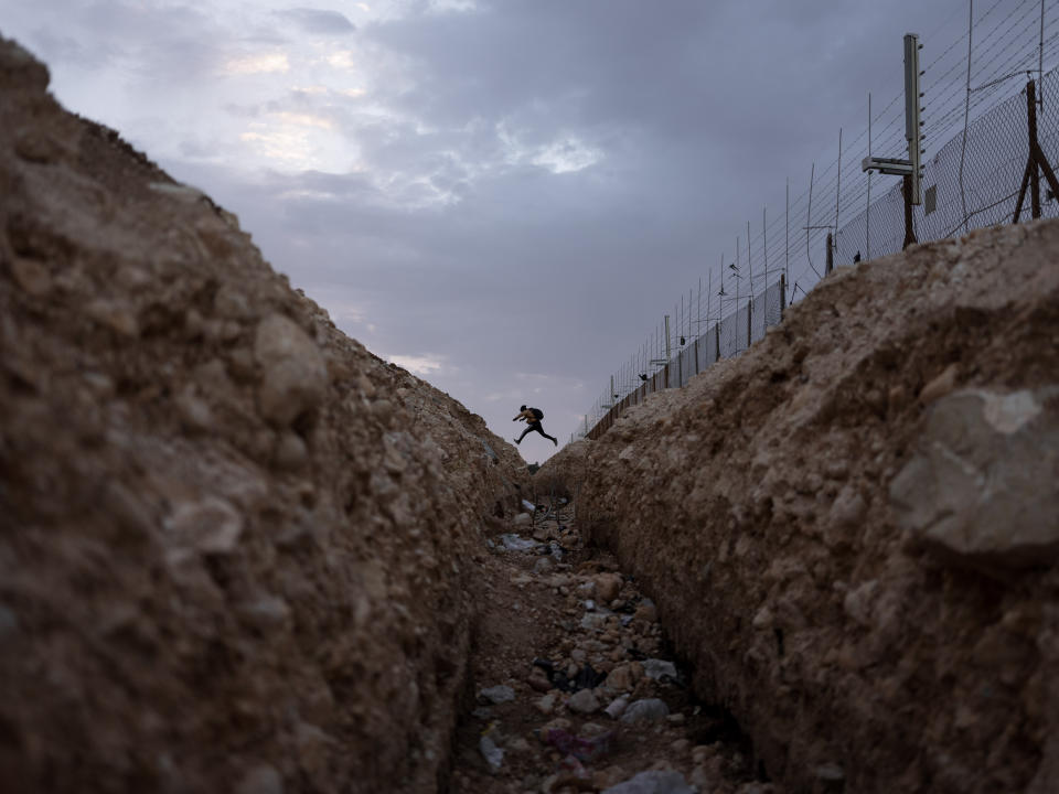 FILE - A Palestinian crosses into Israel from the West Bank through an opening in the Israeli separation barrier near Meitar crossing south of West Bank, March 6, 2022. (AP Photo/Oded Balilty, File)