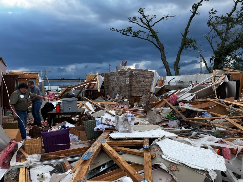 Larry Handsacker, in green shirt, searches through the wreckage of his home near Nevada.