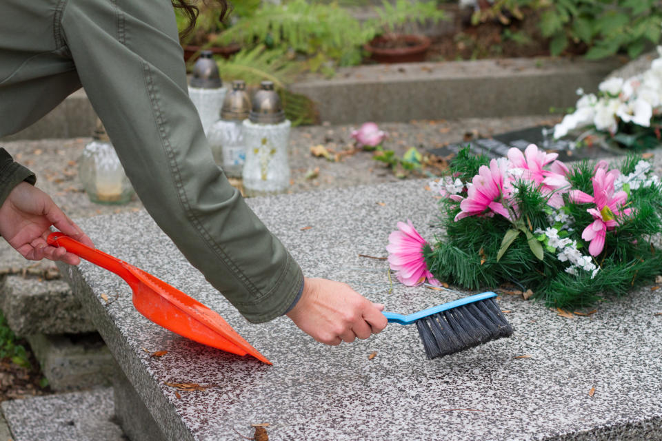 Cleaning grave on cemetery before All Saints' Day closeup