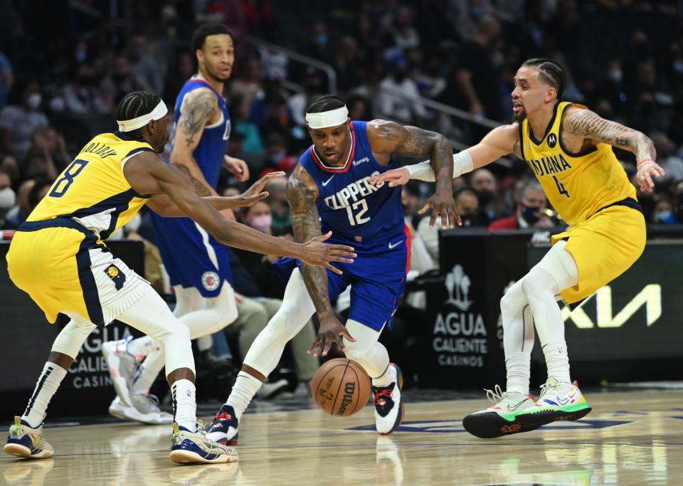 Jan 17, 2022; Los Angeles, California, USA; Los Angeles Clippers guard Eric Bledsoe (12) is defended by Indiana Pacers forward Justin Holiday (8) and guard Duane Washington Jr. (4) in the first half at Crypto.com Arena. Mandatory Credit: Jayne Kamin-Oncea-USA TODAY Sports