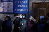 A woman wearing a face mask to help curb the spread of the coronavirus looks back as she lines up with masked residents to receive booster shots against COVID-19 at a vaccination site near a residential area in Beijing, Friday, Oct. 22, 2021. China's capital Beijing has begun offering booster shots against COVID-19, four months before the city and surrounding regions are to host the Winter Olympics. (AP Photo/Andy Wong)